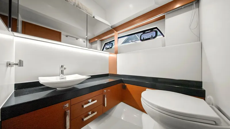 Slide: The Image of Modern Ensuite Bathroom This sleek ensuite bathroom on the Prestige 500 Fly features a contemporary design with high-gloss cabinetry and a stylish vessel sink. The black countertop contrasts elegantly with the wood finishes, while the large mirror and modern fixtures enhance the - 7603804