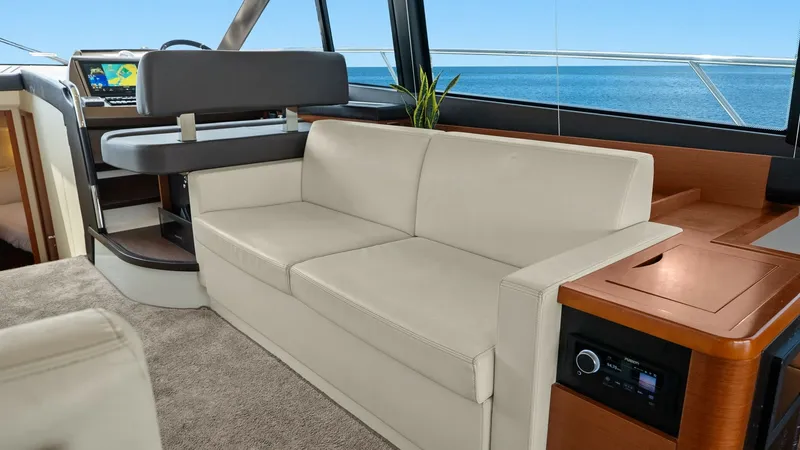 Slide: The Image of Main Salon with Helm Station The main salon of the 2015 Prestige 500 Fly offers a luxurious and inviting space with plush cream-colored seating and expansive windows providing stunning ocean views. The helm station is elegantly integrated, featuring advanced navigation technology for - 7603785