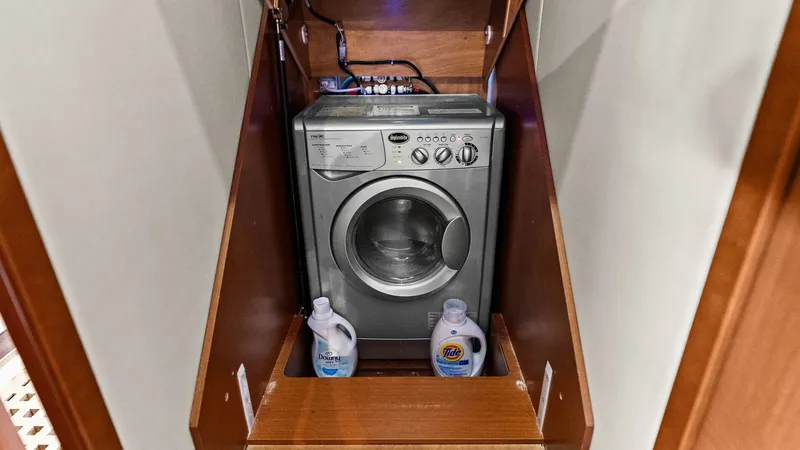 Slide: The Image of Compact Laundry Area with Washer This space-efficient laundry area on the 2015 Prestige 500 Fly features a built-in washer, conveniently tucked away within custom cabinetry. The design ensures practicality and efficient use of space, with storage for laundry essentials. The warm wood fin - 7603817