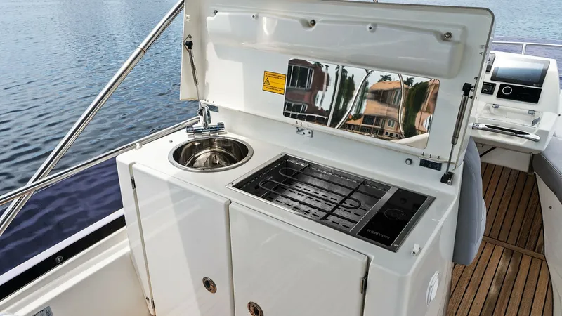 Slide: The Image of Flybridge Galley with Grill and Sink The flybridge of the 2015 Prestige 500 Fly features a compact yet efficient galley area, complete with a stainless steel sink and a built-in grill. The sleek cabinetry provides ample storage, while the polished finish enhances the luxurious feel. This set - 7603767
