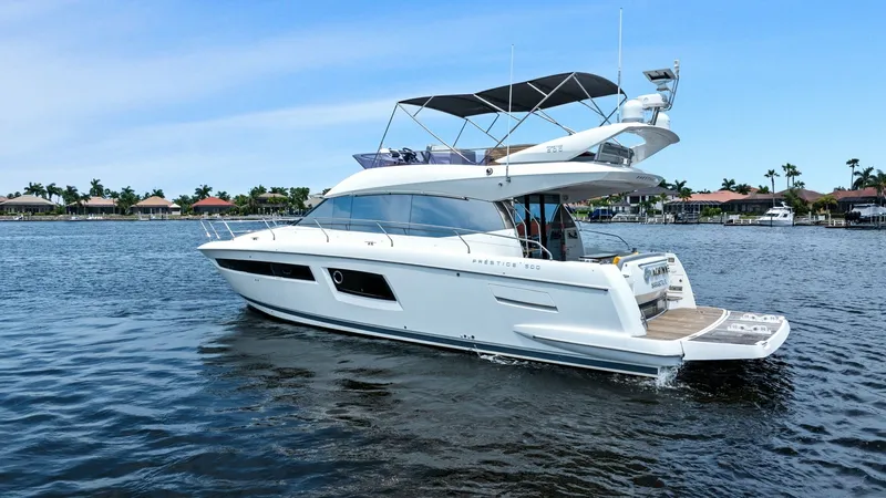 Slide: The Image of Port Side View with Flybridge This image showcases the elegant profile of the 2015 Prestige 500 Fly, highlighting its sleek lines and sophisticated design. The spacious flybridge is equipped with comfortable seating and a modern helm station, offering panoramic views perfect for leisu - 7603834