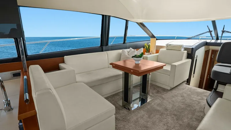 Slide: The Image of Spacious Salon with Panoramic Views This elegant salon aboard the Prestige 500 Fly features plush, cream-colored seating and a stylish wooden coffee table, creating a welcoming and sophisticated atmosphere. Large windows provide breathtaking panoramic views of the open sea, enhancing the se - 7603788