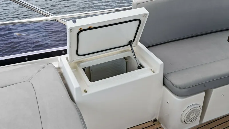 Slide: The Image of Flybridge Seating with Storage Compartment This image showcases a seating area on the flybridge of the 2015 Prestige 500 Fly. The built-in storage compartment is open, providing convenient access to additional space for personal items or refreshments. The teak decking and cushioned seating enhance - 7603769