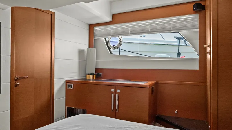 Slide: The Image of Elegant Guest Stateroom Interior This guest stateroom offers a serene retreat with its sophisticated wood finishes and modern design. Ample natural light streams through the large window, enhancing the spacious feel and providing a view of the surrounding seascape. The room features a sl - 7603800
