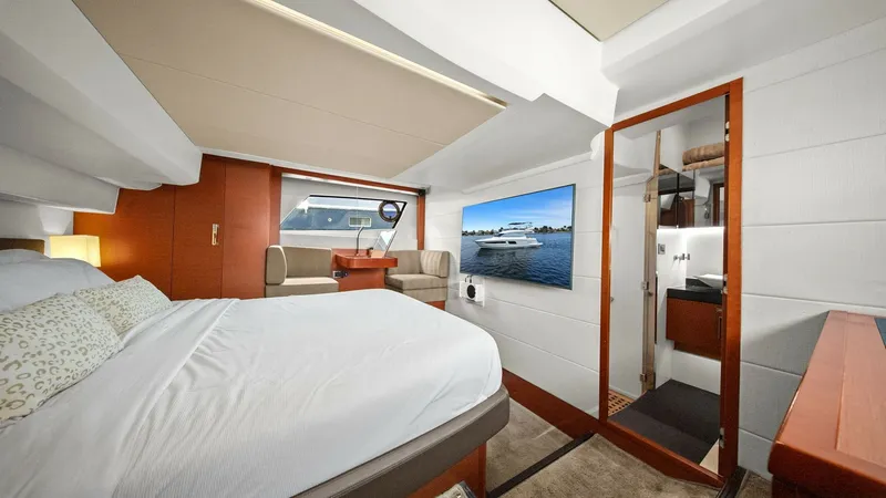 Slide: The Image of Luxurious Forward Master Stateroom The forward master stateroom on the Prestige 500 Fly offers a spacious and inviting retreat. It features a plush double bed with elegant bedding, ample natural light from large windows, and a cozy seating area. Rich wood finishes and a modern ensuite bath - 7603802