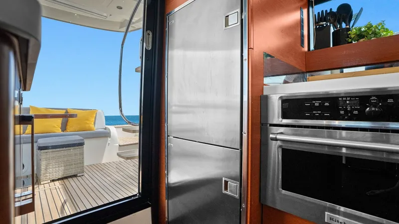 Slide: The Image of Galley with Aft Deck View This image showcases the galley of the 2015 Prestige 500 Fly, featuring sleek stainless steel appliances and elegant wood finishes. The galley opens seamlessly to the aft deck, offering a bright and inviting space with views of the ocean. The outdoor seat - 7603778