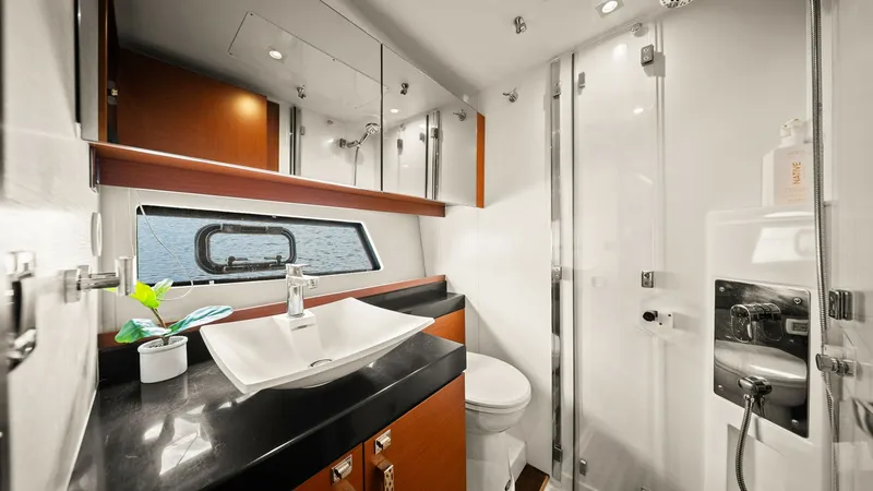 Slide: The Image of Luxurious Ensuite Bathroom This elegant ensuite bathroom aboard the 2015 Prestige 500 Fly features a sleek, modern design with high-gloss wood cabinetry and a spacious glass-enclosed shower. The vessel sink and black countertop add a touch of sophistication, while the ample mirror - 7603811
