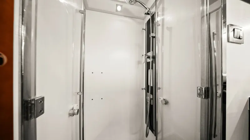 Slide: The Image of Elegant Enclosed Shower Space This image showcases a sleek and modern enclosed shower aboard the 2015 Prestige 500 Fly. The space features pristine white walls and a contemporary overhead shower fixture, offering a luxurious bathing experience. The glass doors and chrome fittings enha - 7603806