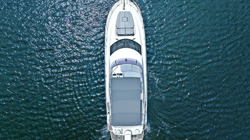 Slide: The Image of Aerial View of Flybridge and Deck This aerial shot of the Prestige 500 Fly showcases the spacious flybridge and sleek deck design. The sunpad at the bow offers a luxurious space for relaxation, while the covered flybridge provides ample seating and a shaded area for socializing. The yacht - 7603830