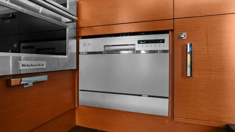 Slide: The Image of Galley with Modern Appliances This image showcases the galley of the Prestige 500 Fly, featuring sleek, integrated appliances. The cabinetry is finished in a rich wood tone, providing a warm and inviting atmosphere. High-end appliances, including a KitchenAid oven, ensure a gourmet co - 7603782