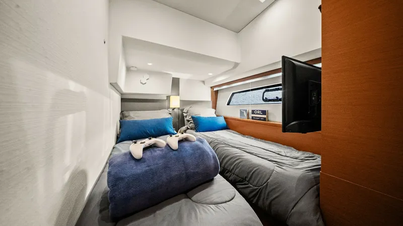 Slide: The Image of Cozy Twin Guest Cabin This inviting twin guest cabin on the 2015 Prestige 500 Fly offers comfortable accommodations with two single beds adorned with plush pillows and bedding. The space is thoughtfully designed, featuring a built-in flat-screen TV for entertainment and a slee - 7603814