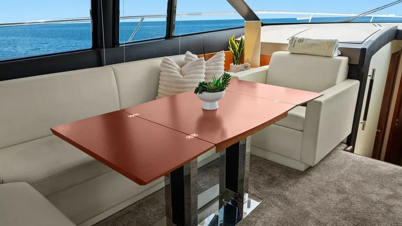 Slide: The Image of Salon Seating with Expandable Table This inviting salon area on the YachtWave features plush, cream-colored seating complemented by a sleek, expandable wooden table. The large windows offer panoramic ocean views, enhancing the space with natural light. The elegant design and comfortable lay - 7603784