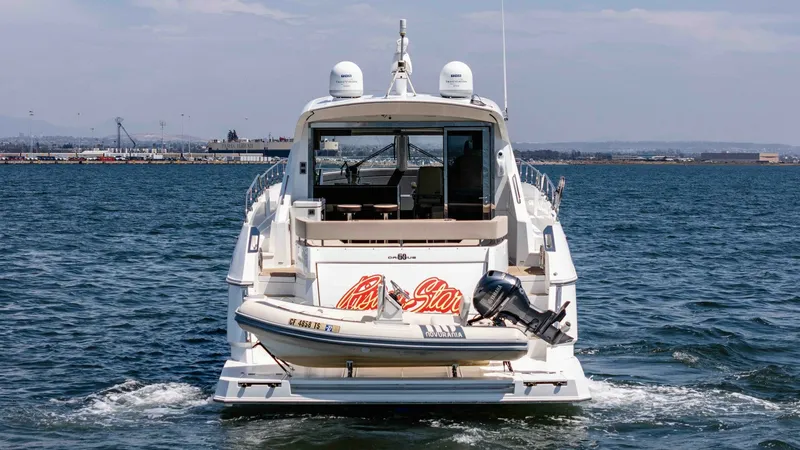 Slide: The Image of 2017 Cruisers 60 Cantius, 'Rising Star' - Aft View with Tender and Swim Platform The aft view of the 2017 Cruisers 60 Cantius 'Rising Star' showcases its sleek swim platform, complete with a mounted tender for convenient excursions. The design elegantly integrates utility and style, with a spacious cockpit visible through the glass do - 7603889