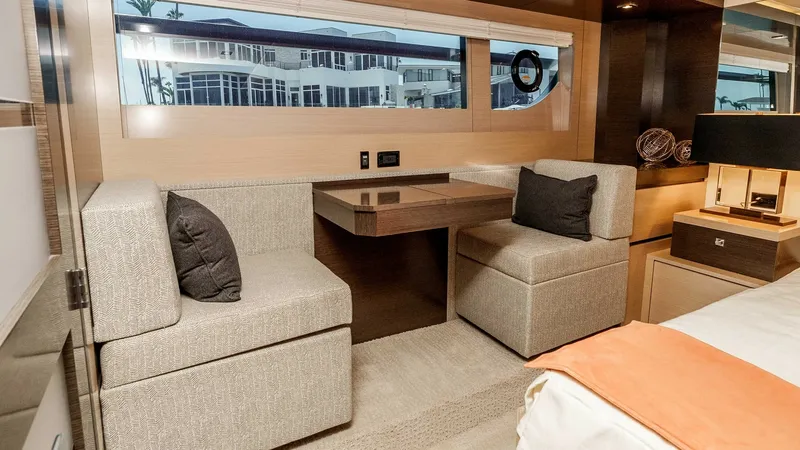 Slide: The Image of 2017 Cruisers 60 Cantius 'Rising Star' - Master Stateroom Lounge Area The master cabin of the 2017 Cruisers 60 Cantius features a cozy lounge area with plush seating and a compact table. The expansive windows allow natural light to flood the space, highlighting the elegant wood finishes and modern design. This inviting area - 7603858
