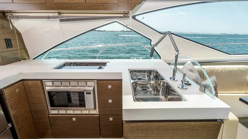 Slide: The Image of 2017 Cruisers 60 Cantius 'Rising Star' - Galley with Ocean View This modern galley on the 2017 Cruisers 60 Cantius features sleek, wood-finished cabinetry and dual stainless steel sinks. The large windows provide stunning ocean views, enhancing the bright and open feel. Equipped with a built-in microwave and ample cou - 7603845