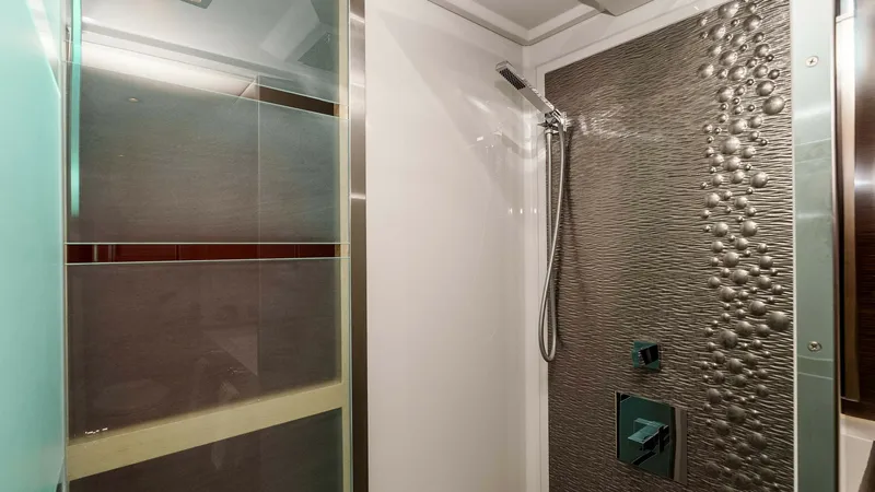 Slide: The Image of 2017 Cruisers 60 Cantius 'Rising Star' - En-Suite Walk-In Shower This elegant en-suite shower aboard the 2017 Cruisers 60 Cantius features a luxury enclosed walk-in shower with frameless glass, rainfall showerhead, handheld wand, and textured metallic accent wall. - 7603861