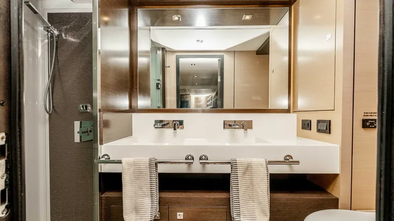 Slide: The Image of 2017 Cruisers 60 Cantius 'Rising Star' - Elegant Master Ensuite Head This elegant ensuite head on the 2017 Cruisers 60 Cantius features a sleek double vanity with modern fixtures and ample storage. The sophisticated design includes a spacious shower area with high-end finishes. Ambient lighting enhances the warm wood tones - 7603860