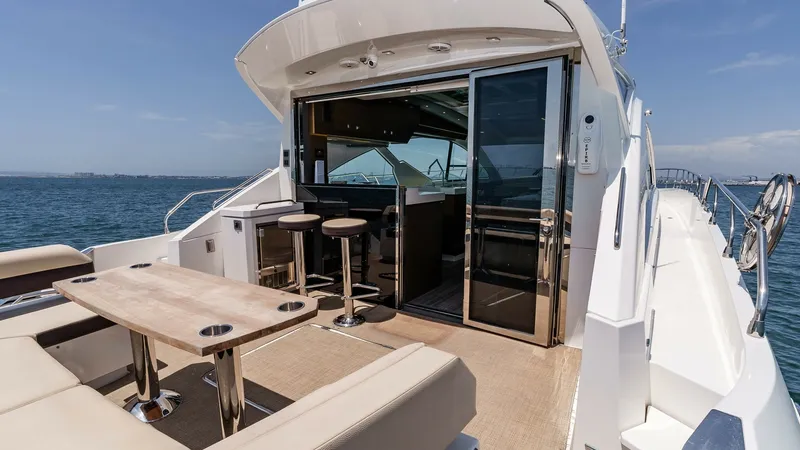 Slide: The Image of 2017 Cruisers 60 Cantius, 'Rising Star' - Features a Luxurious Seating Area with a Sleek, Modern Table Perfect for Entertaining. The Seamless Transition to the Interior is Facilitated by Large Sliding Glass Doors, Opening up to a Stylish Bar with High Sto The aft deck of the 2017 Cruisers 60 Cantius 'Rising Star' features a luxurious seating area with a sleek, modern table perfect for entertaining. The seamless transition to the interior is facilitated by large sliding glass doors, opening up to a stylish - 7603873