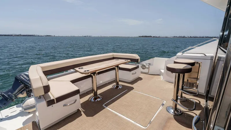 Slide: The Image of 2017 Cruisers 60 Cantius, 'Rising Star' - Spacious Aft Deck with Seating The aft deck of the 2017 Cruisers 60 Cantius features elegant wraparound seating with a stylish wooden table, ideal for alfresco dining. This area is complemented by two sleek bar stools, offering additional space for relaxation and entertainment. The ope - 7603876
