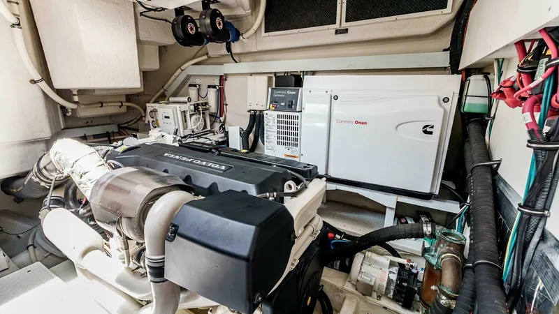 Slide: The Image of 2017 Cruisers 60 Cantius, 'Rising Star' - Engine Room with an Onan Generator System The engine room of the 2017 Cruisers 60 Cantius, 'Rising Star', is equipped with a robust Volvo Penta engine and a Cummins Onan generator. The space is meticulously organized, showcasing efficient wiring and accessible components, ensuring ease of mainten - 7603869