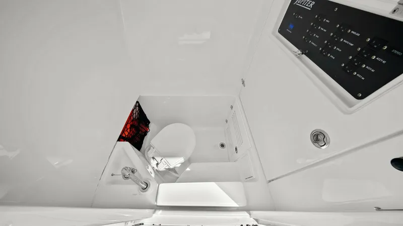 Slide: The Image of Compact Cabin Head with Controls This image showcases the compact and efficient head compartment on the Jupiter 30 HFS. The space features a sleek marine toilet with adjacent storage, ensuring convenience and functionality. The overhead control panel adds modernity and ease of access to - 7718742