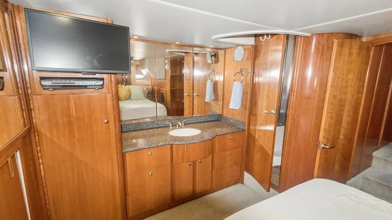 Slide: The Image of Master Stateroom Vanity Area The 2005 Meridian 540 Pilothouse features a master stateroom with a well-appointed vanity area. The space includes a sleek granite countertop, ample storage, and a mounted flat-screen TV for entertainment. The warm wood finishes and soft lighting create a - 7721601
