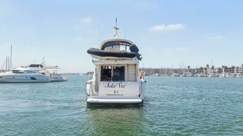 Slide: The Image of Aft View of 2005 Meridian 540 The aft view of the 2005 Meridian 540 Pilothouse, JOLIE VIE, showcases its elegant design and spacious swim platform. The vessel's name is prominently displayed, with ample space for easy boarding and waterside enjoyment. The flybridge can be seen above, - 7721629
