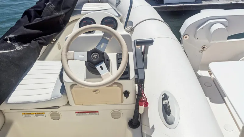 Slide: The Image of Helm Station with Steering Wheel This image showcases the helm station of a tender boat, featuring a well-maintained steering wheel and essential controls. The layout provides easy access to the dashboard gauges and throttles, ensuring a smooth and efficient navigation experience. The se - 7721625