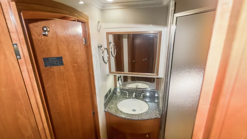 Slide: The Image of Elegant Bathroom with Vanity and Shower The bathroom aboard the 2005 Meridian 540 Pilothouse exudes elegance with its polished wood cabinetry and sleek granite countertop. A well-sized vanity with an integrated sink is complemented by a large mirror, enhancing the sense of space. The frosted gl - 7721612