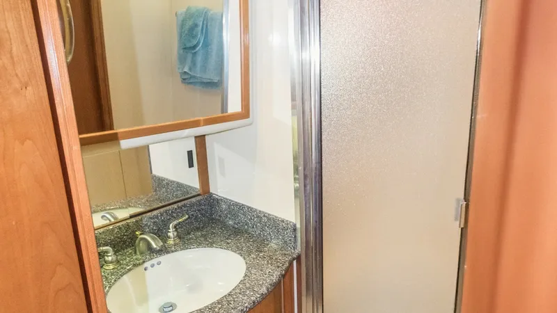 Slide: The Image of En Suite Bathroom with Shower This elegant en suite bathroom on the Meridian 540 Pilothouse features a sleek granite countertop with an undermount sink, complemented by polished chrome fixtures. The frosted glass shower enclosure adds a touch of modern sophistication, while the wooden - 7721611