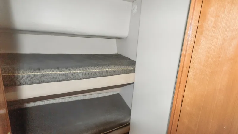 Slide: The Image of Cozy Bunk Cabin Area This image showcases a compact bunk cabin with two neatly arranged berths, ideal for accommodating guests or crew. The space features simple, streamlined bedding, providing comfort and functionality. The warm wood accents add a touch of elegance, compleme - 7721617