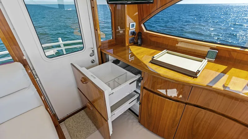 Slide: The Image of Galley with Ocean View This elegant galley on the 2018 Viking 62 Enclosed Bridge features rich wood cabinetry and a sleek countertop, offering both style and functionality. The large window provides a stunning ocean view, enhancing the open and airy feel. Ample storage and mode - 7751283