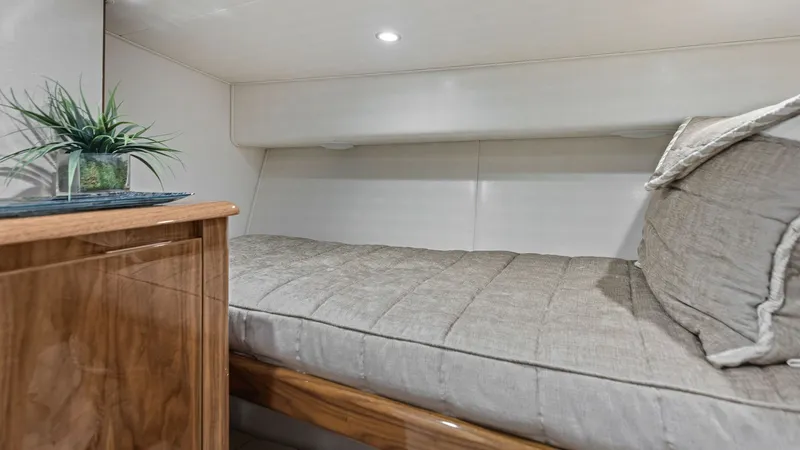 Slide: The Image of Cozy Guest Cabin with Bedding This inviting guest cabin on the 2018 Viking 62 Enclosed Bridge features a comfortable single berth with soft, neutral bedding. The warm wood cabinetry adds a touch of elegance, while recessed lighting creates a peaceful ambiance. Thoughtfully designed st - 7751259