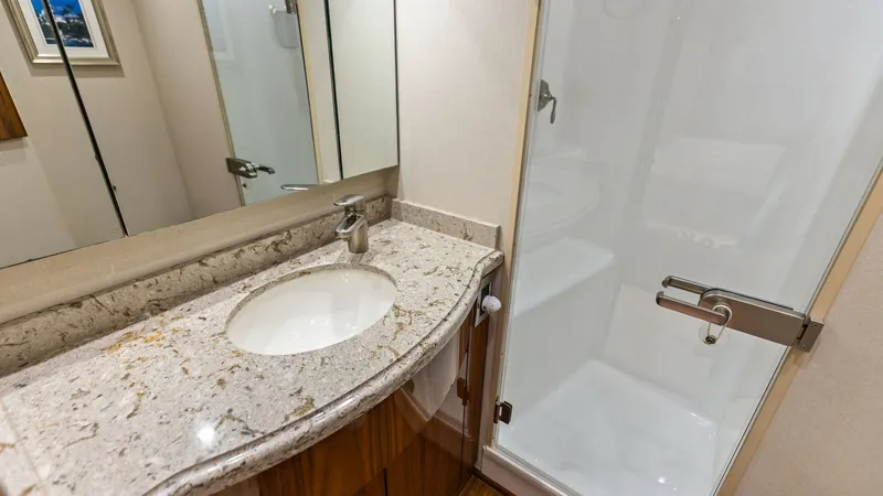 Slide: The Image of Luxurious En-Suite Bathroom This elegant en-suite bathroom on the Viking 62 Enclosed Bridge features a beautifully crafted granite countertop with an undermount sink. The space is complemented by a spacious, glass-enclosed shower, offering both functionality and style. High-quality - 7751248