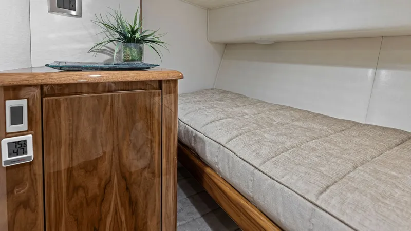 Slide: The Image of Guest Cabin with Plush Bedding This cozy guest cabin on the 2018 Viking 62 Enclosed Bridge offers a comfortable retreat with its plush bedding and elegant wood cabinetry. The neutral tones create a serene atmosphere, complemented by modern fixtures and a digital climate control system - 7751260