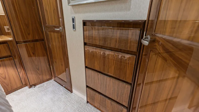 Slide: The Image of Luxurious Wood-Finished Interior Cabinetry This image showcases the exquisite wood-finished cabinetry within the 2018 Viking 62 Enclosed Bridge. The polished wood surfaces and elegant paneling reflect a commitment to detail and craftsmanship. Soft carpeting adds warmth and comfort, enhancing the l - 7751241