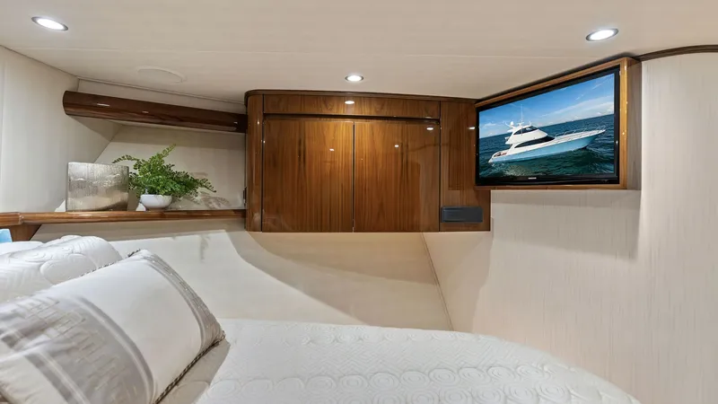 Slide: The Image of Guest Stateroom with Entertainment System This inviting guest stateroom on the Viking 62 Enclosed Bridge features a plush queen-sized bed with elegant bedding. The room is equipped with a mounted flat-screen TV for entertainment and showcases exquisite wood cabinetry for storage. Soft recessed li - 7751253