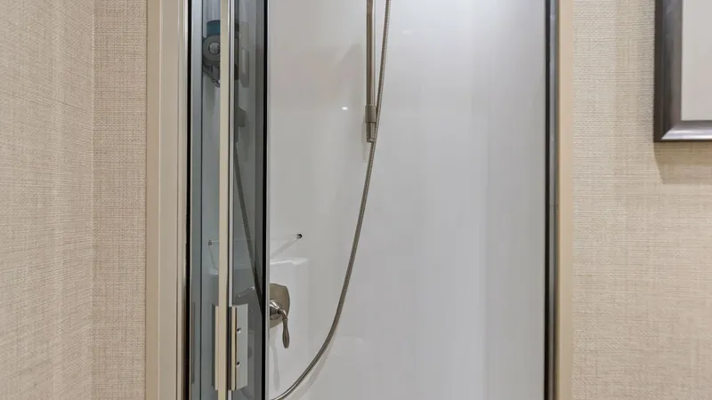 Slide: The Image of Elegant Enclosed Shower Stall This modern enclosed shower stall on the Viking 62 Enclosed Bridge offers sleek design and functionality. The glass door and chrome fixtures provide a contemporary feel, complementing the textured wall finish. Ideal for refreshing moments at sea, this spa - 7751255