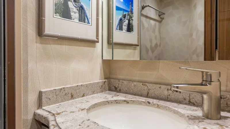 Slide: The Image of Luxurious Vanity in Guest Head This elegant guest head features a beautifully crafted stone countertop with a modern, sleek faucet. The subtle, textured wall design complements the framed artwork, adding a touch of sophistication. Ample lighting and a mirrored wall enhance the space, c - 7751263