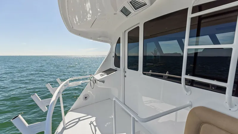 Slide: The Image of Starboard Walkaround and Cockpit Access This image showcases the starboard walkaround of the Viking 62 Enclosed Bridge, featuring seamless access to the cockpit area. The sleek design includes stainless steel railings and rod holders, perfect for fishing enthusiasts. Large windows offer panoram - 7751285