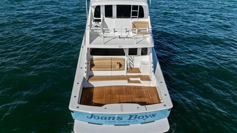 Slide: The Image of Aft Deck and Enclosed Bridge View This image showcases the sleek aft deck of the 2018 Viking 62 Enclosed Bridge, 'Joan's Boys'. The spacious teak deck provides ample room for outdoor activities, complemented by comfortable seating areas. The enclosed bridge offers a commanding view, enhan - 7751306