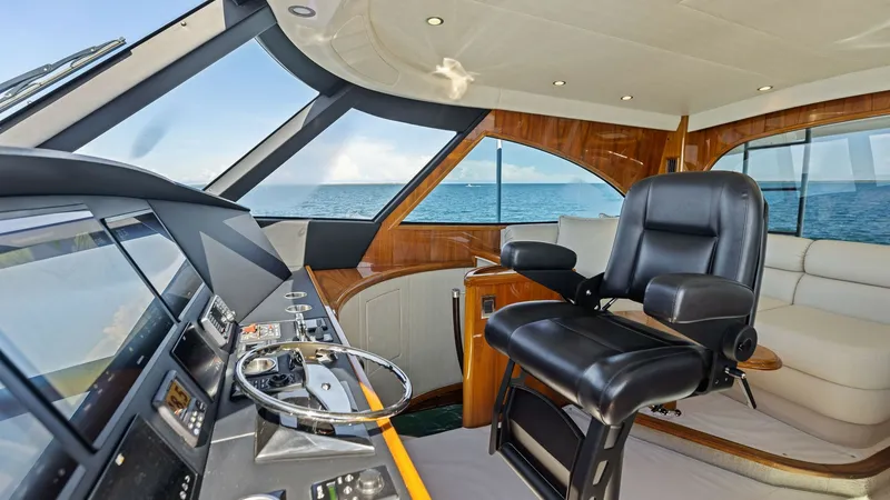 Slide: The Image of Enclosed Bridge Helm Station The helm station of the Viking 62 Enclosed Bridge offers a commanding view with its expansive windows, providing excellent visibility for navigation. The space features a luxurious captain's chair and state-of-the-art instrumentation, ensuring precise con - 7751280