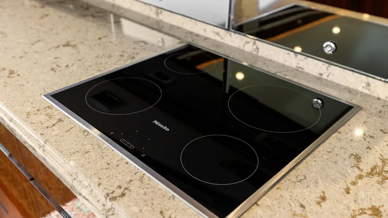 Slide: The Image of Galley Induction Cooktop and Counter This image showcases the sleek induction cooktop set into the luxurious countertop of the Viking 62 Enclosed Bridge galley. The modern Miele cooktop offers efficient cooking capabilities, complemented by the polished finish of the counter, enhancing the s - 7751229