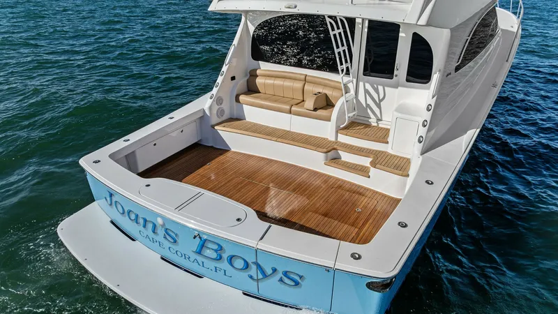 Slide: The Image of Spacious Aft Deck with Seating The aft deck of the 2018 Viking 62 Enclosed Bridge, 'Joan's Boys', boasts a spacious and inviting layout ideal for relaxation or entertaining. The teak flooring complements the comfortable built-in seating, offering a luxurious touch. This area provides s - 7751309