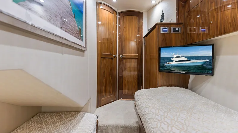 Slide: The Image of Guest Stateroom with Twin Berths This inviting guest stateroom on the 2018 Viking 62 Enclosed Bridge offers twin berths with plush, patterned bedding for a comfortable stay. The warm wooden cabinetry and doors complement the modern amenities, including a flat-screen TV mounted for entert - 7751271