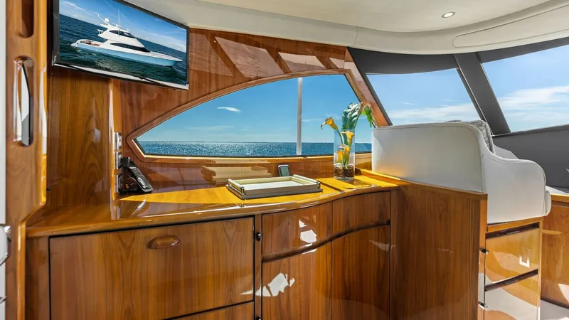 Slide: The Image of Enclosed Bridge Helm Station The enclosed bridge of the 2018 Viking 62 offers a commanding view with its expansive windows, providing ample natural light and stunning ocean vistas. High-gloss wood finishes and a sleek helm station enhance the luxurious ambiance. A mounted TV and thou - 7751282
