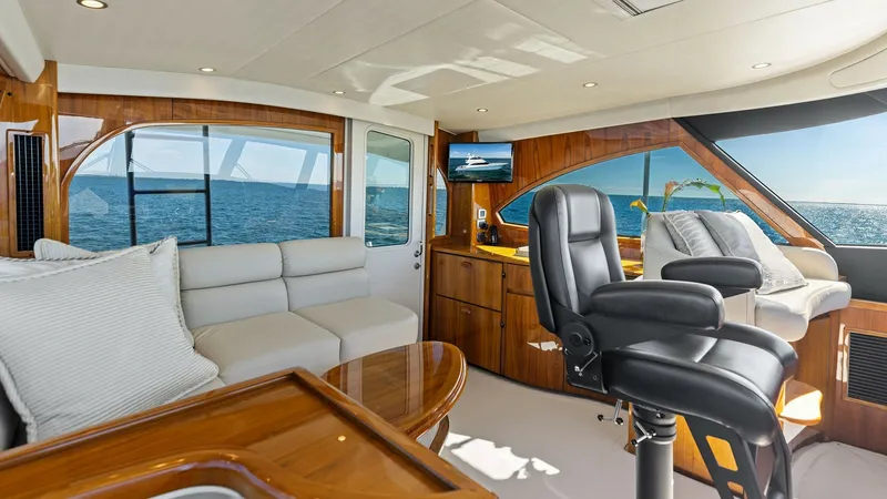 Slide: The Image of Enclosed Bridge Helm and Seating Area The enclosed bridge of the Viking 62 features a luxurious helm station with a plush captain's chair, offering commanding views through panoramic windows. The seating area includes a comfortable L-shaped sofa and a polished wooden table, creating a perfect - 7751274