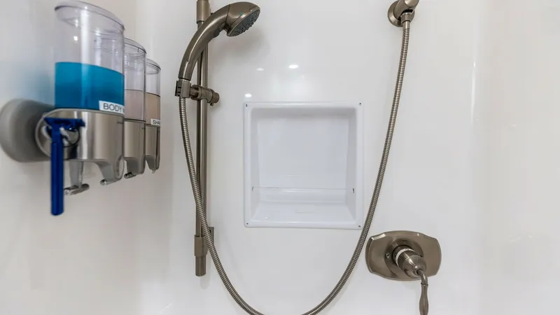 Slide: The Image of Luxury Shower with Modern Fixtures This image showcases the elegant shower area on the Viking 62 Enclosed Bridge model. Featuring sleek, modern fixtures with a handheld showerhead and convenient wall-mounted dispensers, this space combines functionality with luxury. The clean, white surfac - 7751245