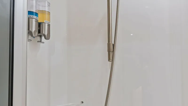 Slide: The Image of Modern Shower Enclosure Detail This image showcases the sleek shower enclosure aboard the Viking 62 Enclosed Bridge. The space is equipped with convenient body wash and shampoo dispensers, highlighting the vessel's focus on luxury and practicality. The clean, minimalist design features - 7751257