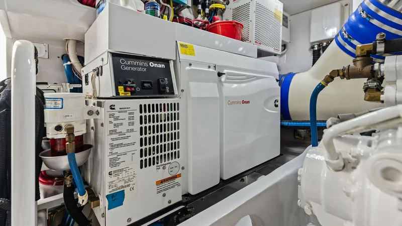 Slide: The Image of Engine Room with Cummins Onan Generator The engine room of the 2018 Viking 62 Enclosed Bridge showcases a Cummins Onan generator, ensuring reliable power for extended voyages. The space is meticulously organized, featuring high-quality components and efficient layout for optimal performance. Br - 7751301